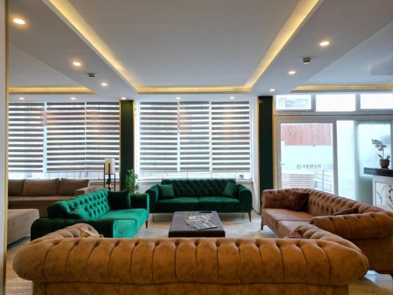Elegante salón lobby del Akman City Hotel con sofás Chesterfield verdes y marrones y techo iluminado