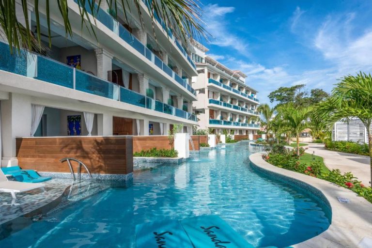 Piscina lazy river con tumbonas azules junto al edificio del Sandals Dunns River All Inclusive