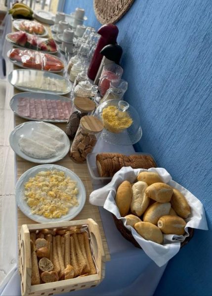 Buffet de desayuno con panes, huevos revueltos, embutidos y frutas frescas en Hotel Sol Brasil