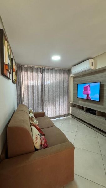 Sala de estar con sofá marrón y televisor del apartamento Landscape Beira Mar Meireles en Fortaleza