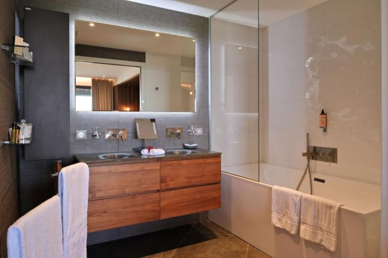 Baño moderno con bañera, ducha de cristal y doble lavabo en madera del Hôtel Le Week End