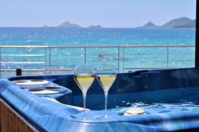 Jacuzzi con copas de vino blanco y vistas al mar turquesa en el Hôtel Le Week End