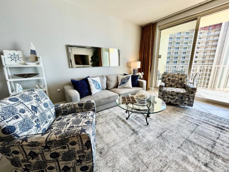 Salón luminoso con sofá, sillones y mesa de cristal en condo frente al mar en Panama City Beach