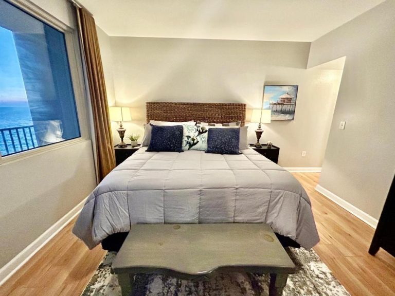 Habitación con cama doble, cabecero de mimbre y vista al mar en condo frente a la playa de Panama City