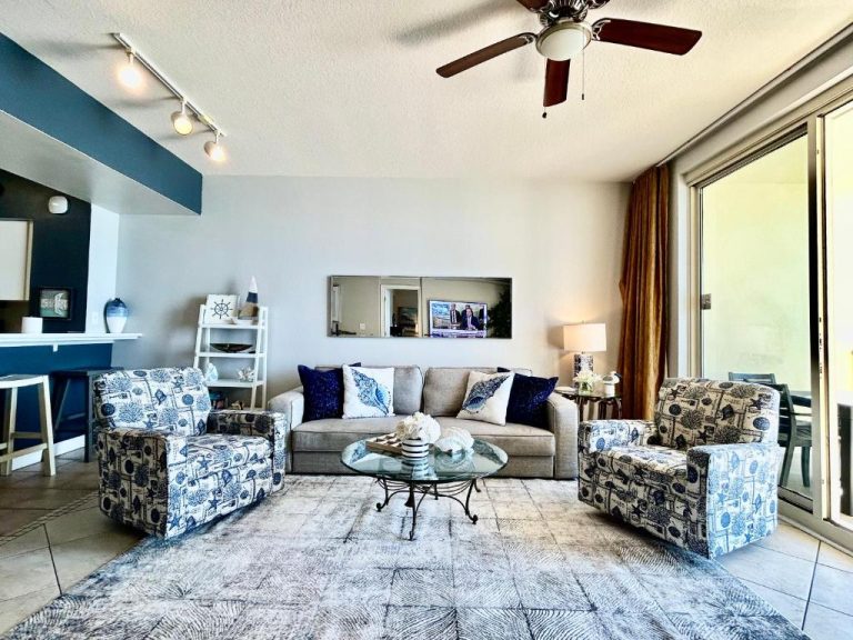 Sala de estar con sofá y sillones decorados en azul del condo frente al mar en Panama City Beach