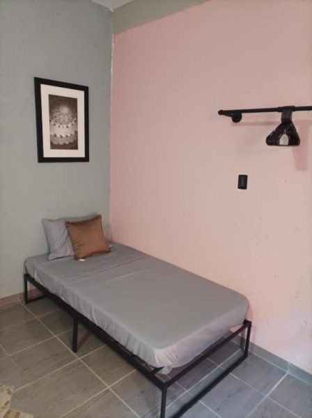 Habitación individual sencilla con cama de metal y perchero en Habitaciones Dos Antonios