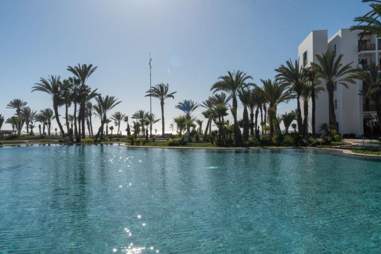 Piscina exterior con aguas cristalinas y palmeras tropicales del hotel The View Agadir en Marruecos