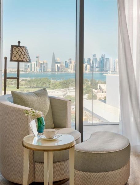Suite de lujo con sillón elegante y vistas panorámicas al skyline de Doha en Mandarin Oriental