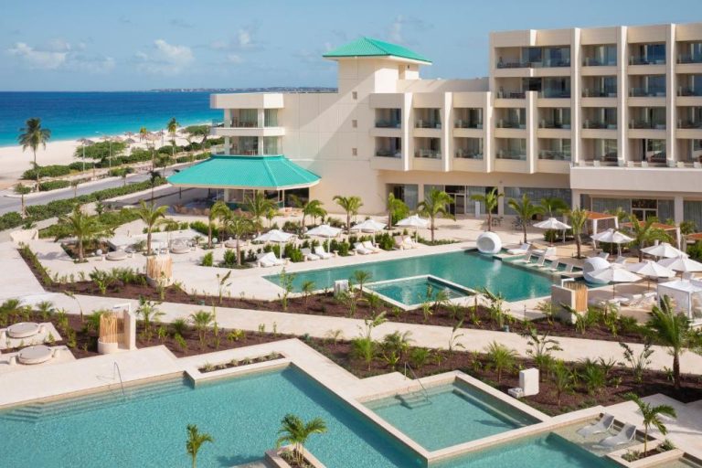 Piscinas exteriores con tumbonas y palmeras del JOIA Aruba by Iberostar frente a la playa