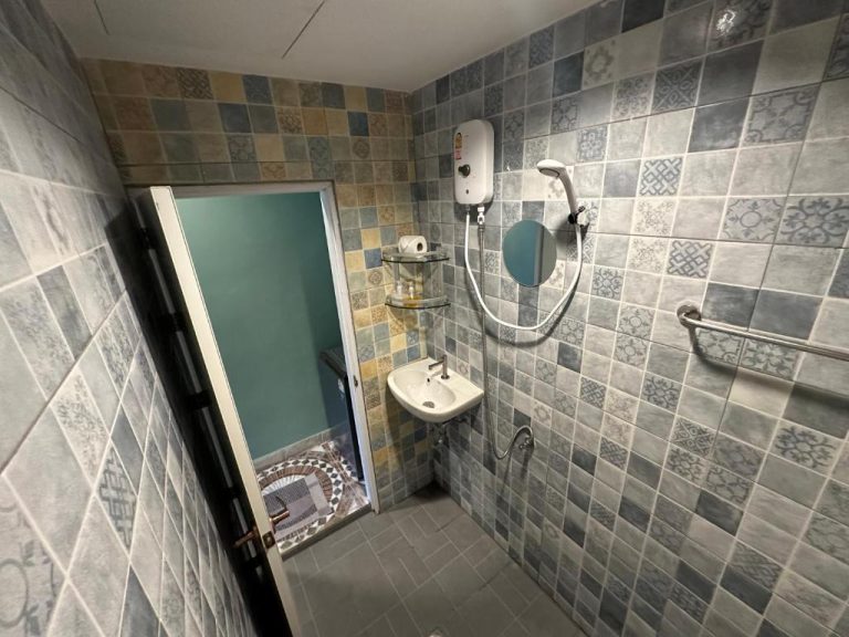Baño con ducha eléctrica, lavabo y azulejos decorativos del hotel Soul of Lanta en Tailandia