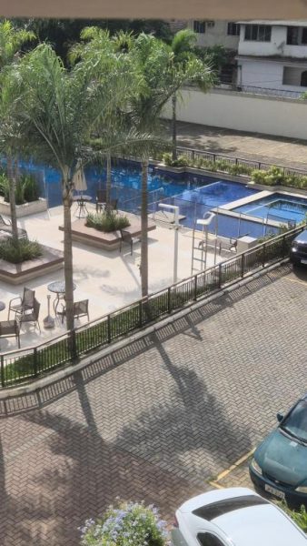 Piscina exterior con palmeras y zona de relax del Studio 210, rodeada de aparcamiento privado