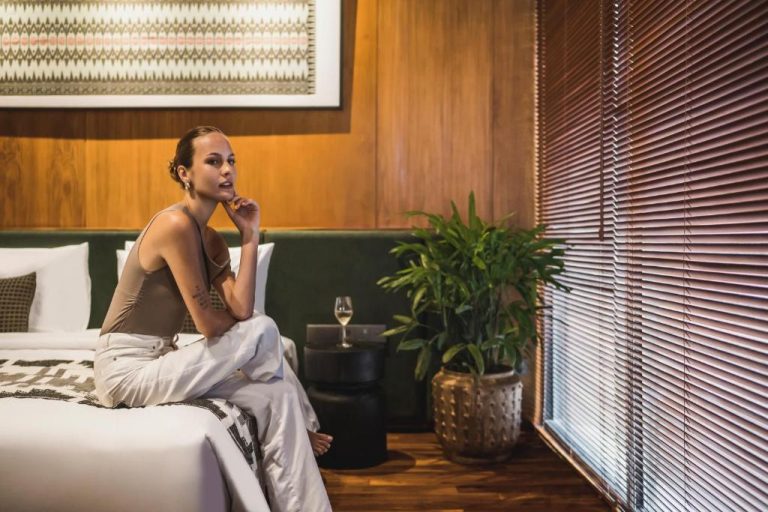 Mujer relajada en habitación suite de lujo del hotel iSuite by Ekosistem con decoración moderna y madera