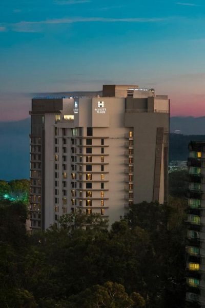 Vista nocturna de la fachada exterior del Hyatt Place Nairobi Westlands rodeado de vegetación al atardecer