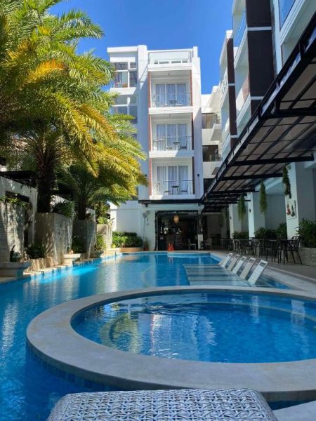 Piscina exterior con jacuzzi y palmeras tropicales del Boracay Haven Suites en Filipinas