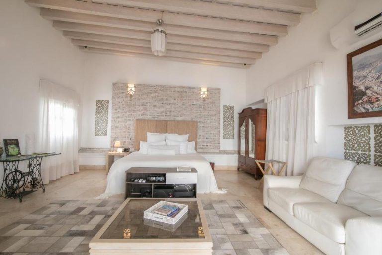 Suite rústica con cama doble, sofá blanco y techo de vigas en Hotel Boutique Don Pepe