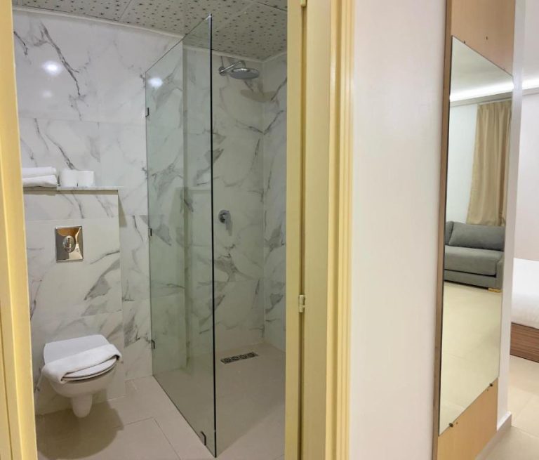 Baño moderno con ducha de lluvia y paredes de mármol blanco en Hotel Anna Agadir