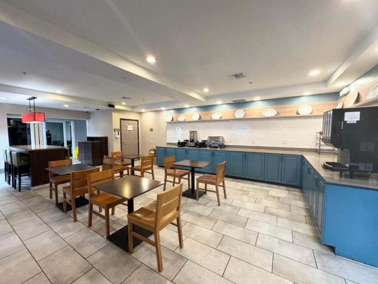 Salón de desayuno buffet con mesas y cocina del Country Inn & Suites by Radisson Port Charlotte FL