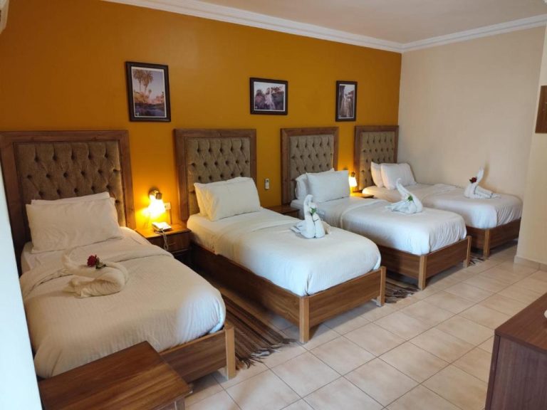 Habitación cuádruple con cuatro camas individuales y cabeceros tapizados en el Mariam Hotel