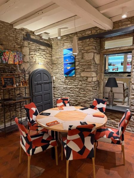 Comedor rústico con paredes de piedra y sillas coloridas en Hotel Restaurant Lesage