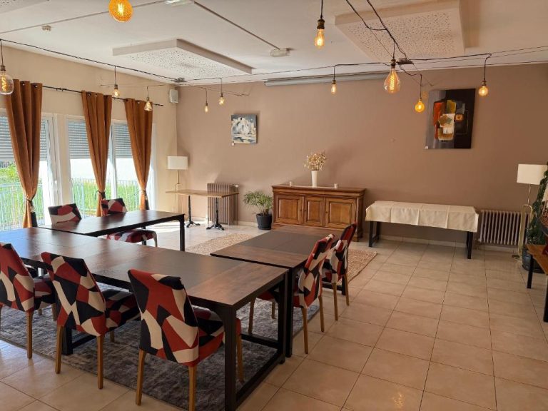 Amplio salón comedor del Hotel Restaurant Lesage con mesas de madera y sillas tapizadas en rojo