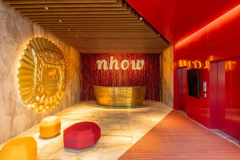 Recepción principal del hotel Nhow Lima con decoración dorada, iluminación roja y arte precolombino