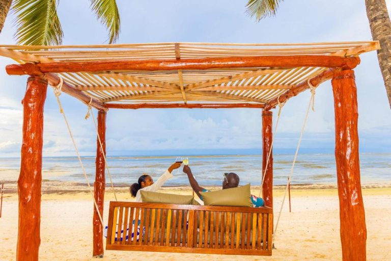 Pareja brindando en pérgola de madera frente a la playa del PrideInn Flamingo Beach Resort & Spa Mombasa
