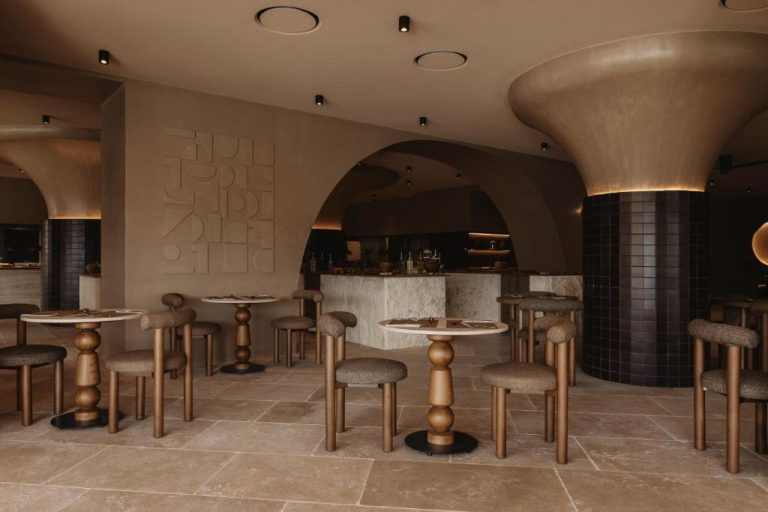 Restaurante de diseño moderno con arcos y mesas redondas de mármol en Seaside A Lifestyle Resort Adults Only