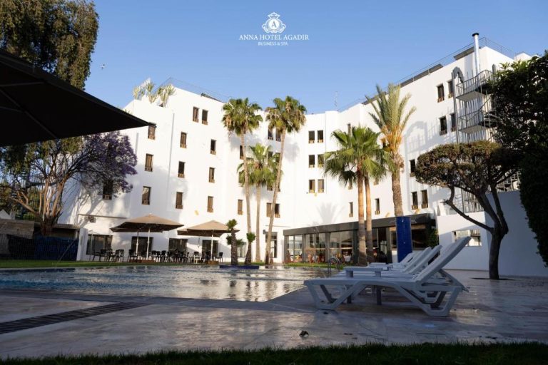 Piscina exterior con tumbonas y palmeras del Anna Hotel Agadir Business & Spa en Marruecos