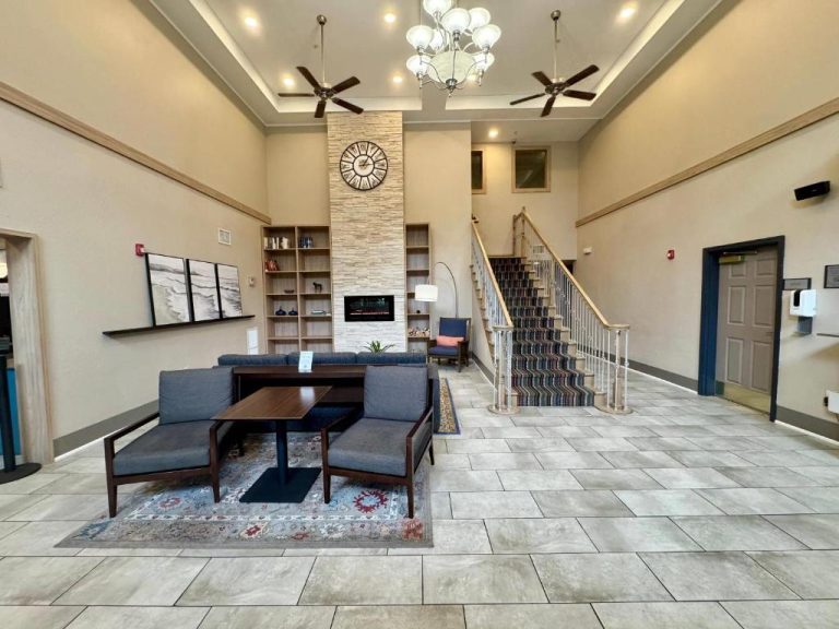 Lobby amplio con chimenea, sofás y escalera del Country Inn & Suites by Radisson Port Charlotte FL