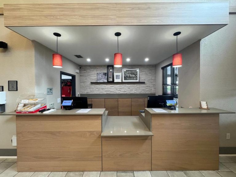 Recepción moderna con mostrador de madera y lámparas rojas del Country Inn & Suites Port Charlotte, FL
