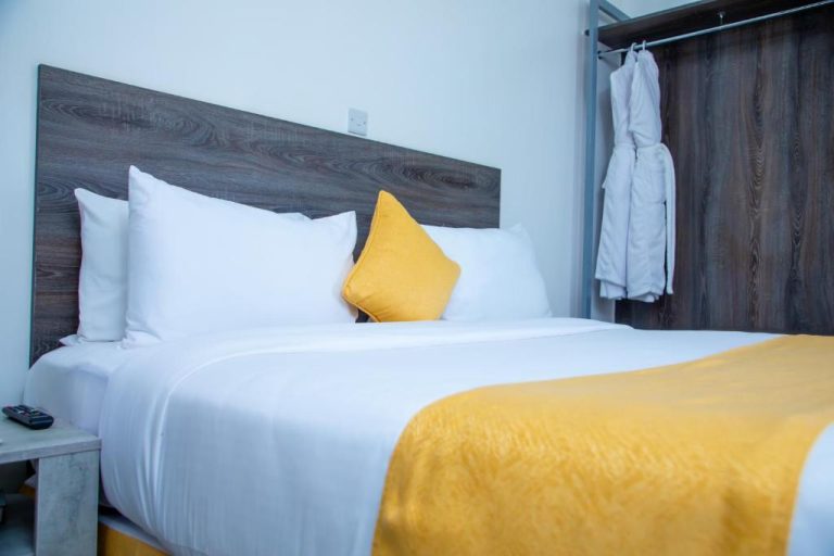 Habitación doble con cama king size y ropa de cama blanca y amarilla en Kisimani Eco Resort & Spa