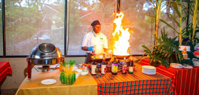 Chef preparando espectáculo de cocina en vivo con llamas en el restaurante de Kisimani Eco Resort & Spa