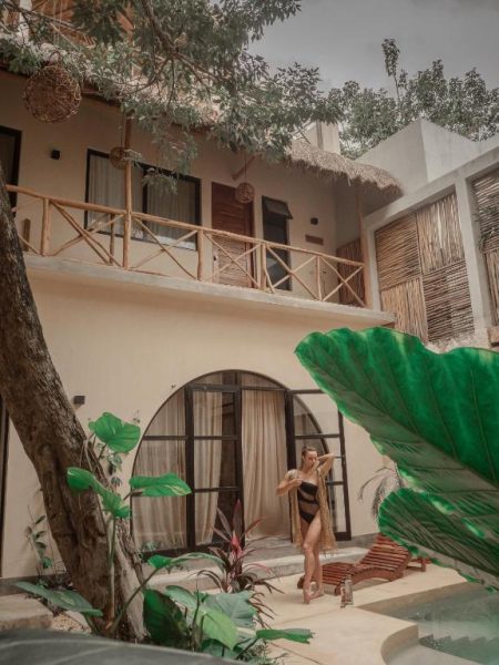 Patio exterior con piscina y vegetación tropical en Casa Kobaab Tulum, con terraza de madera
