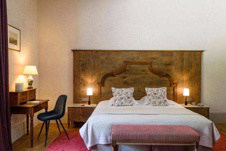 Habitación clásica con gran cabecero de madera tallada y decoración elegante en Château de Saulon