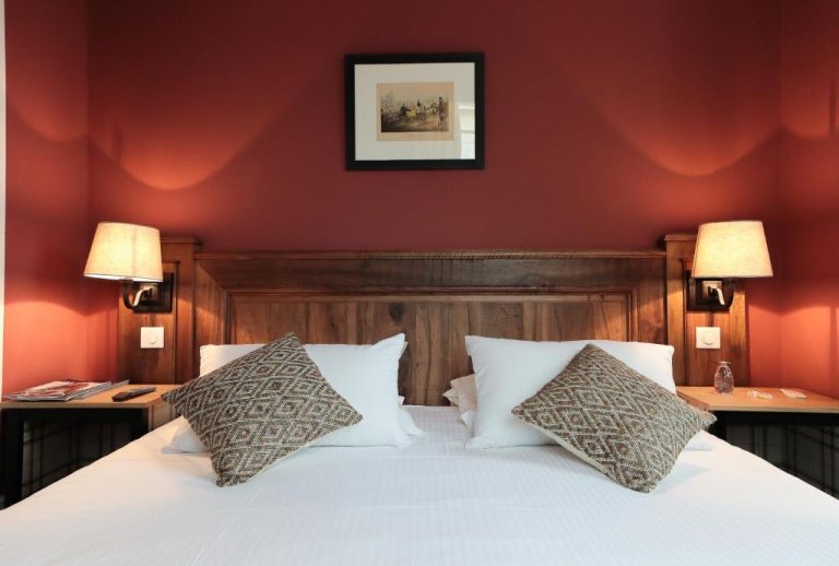 Habitación doble con cabecero de madera y pared roja en Château de Saulon