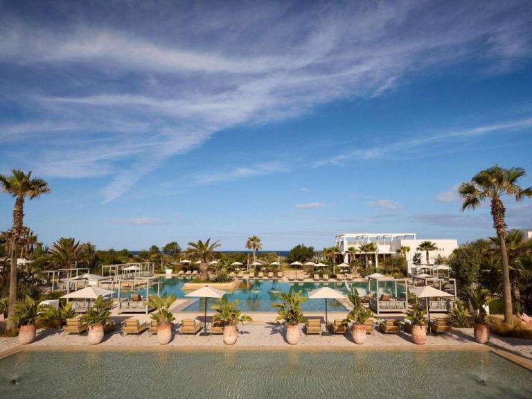 Piscina exterior con tumbonas y palmeras del Sofitel Agadir Thalassa Sea & Spa con vistas al mar