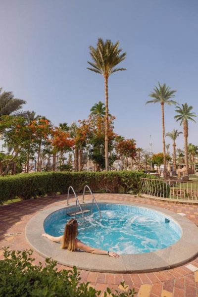 Jacuzzi exterior circular con aguas turquesas rodeado de palmeras en el Hotel Jaz Fayrouz