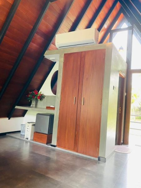 Habitación con armario de madera y techo en forma de A del hotel Avinka Grand con aire acondicionado