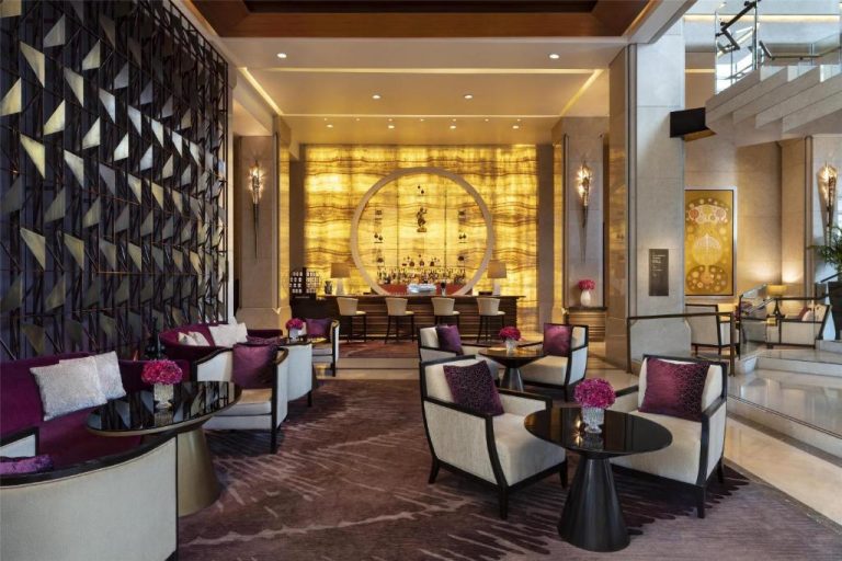 Elegante lobby bar del Siam Kempinski Hotel Bangkok con sillones en tonos dorados y púrpura