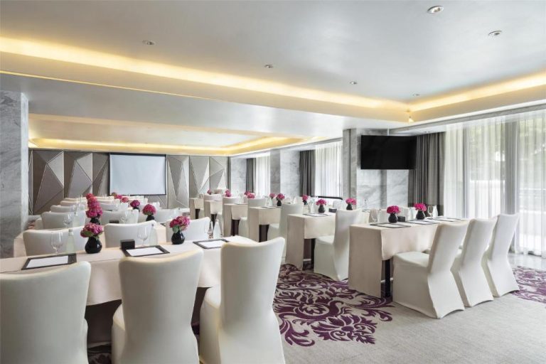 Sala de reuniones con mesas blancas y flores rosas en el Siam Kempinski Hotel Bangkok