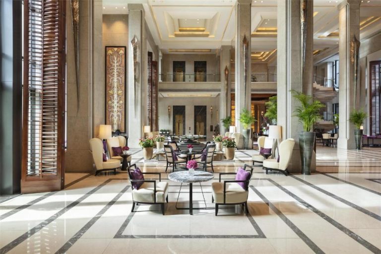 Elegante lobby de mármol con zonas de descanso y decoración floral del Siam Kempinski Hotel Bangkok
