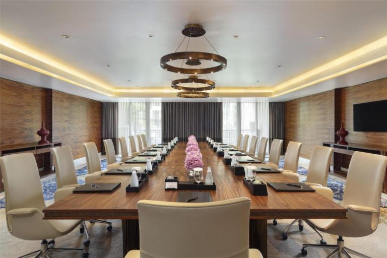 Sala de reuniones ejecutiva con gran mesa de madera y sillas de cuero en el Siam Kempinski Hotel Bangkok