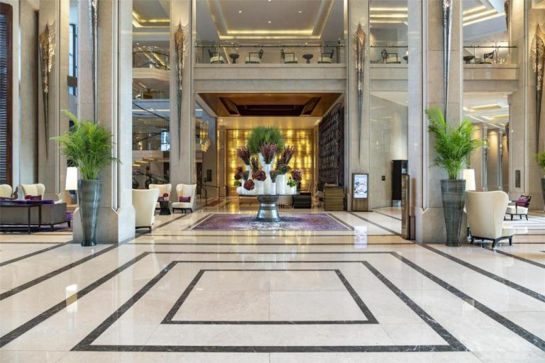 Lujoso lobby del Siam Kempinski Hotel Bangkok con suelos de mármol, columnas y decoración floral