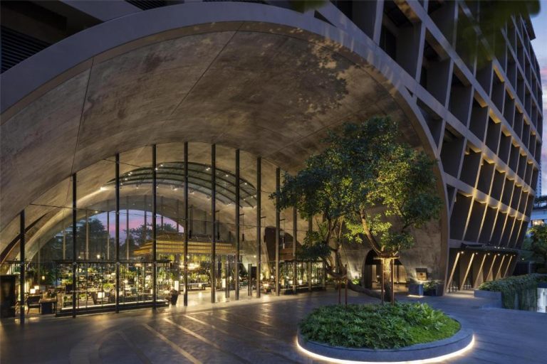 Impresionante lobby con arco de piedra y jardín interior iluminado del Sindhorn Kempinski Hotel Bangkok