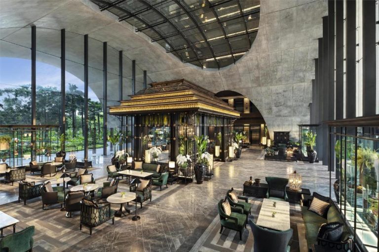 Lujoso lobby lounge del Sindhorn Kempinski Hotel Bangkok con decoración dorada y jardines tropicales