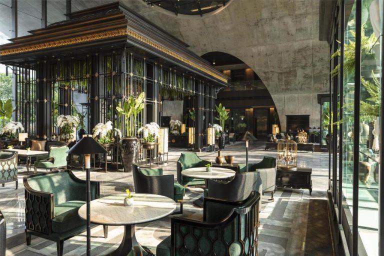 Elegante lobby lounge del Sindhorn Kempinski Hotel Bangkok con sillones verdes y decoración tropical