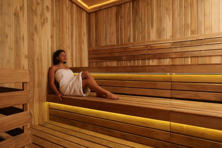Mujer relajándose en la sauna de madera del InterContinental Real Lima Miraflores con iluminación cálida
