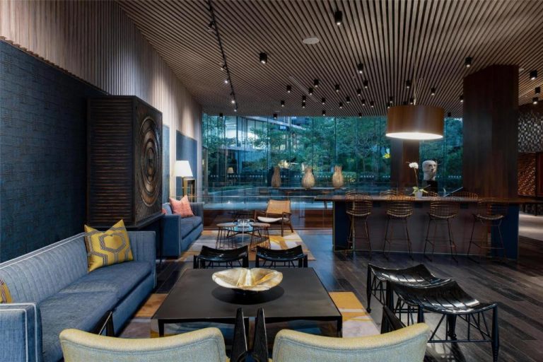 Elegante lobby bar del Hyatt Centric San Isidro Lima con sofás azules, taburetes dorados y gran ventanal