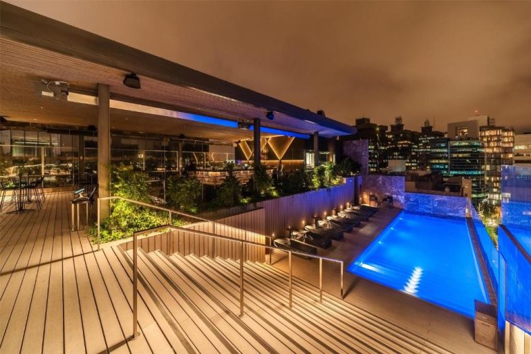Piscina rooftop iluminada de noche con terraza y vistas a la ciudad en Hyatt Centric San Isidro Lima