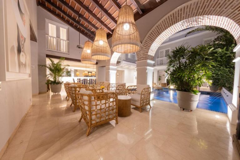 Lobby con sillones de ratán y piscina interior del hotel Casa La Merced by Mustique en Cartagena